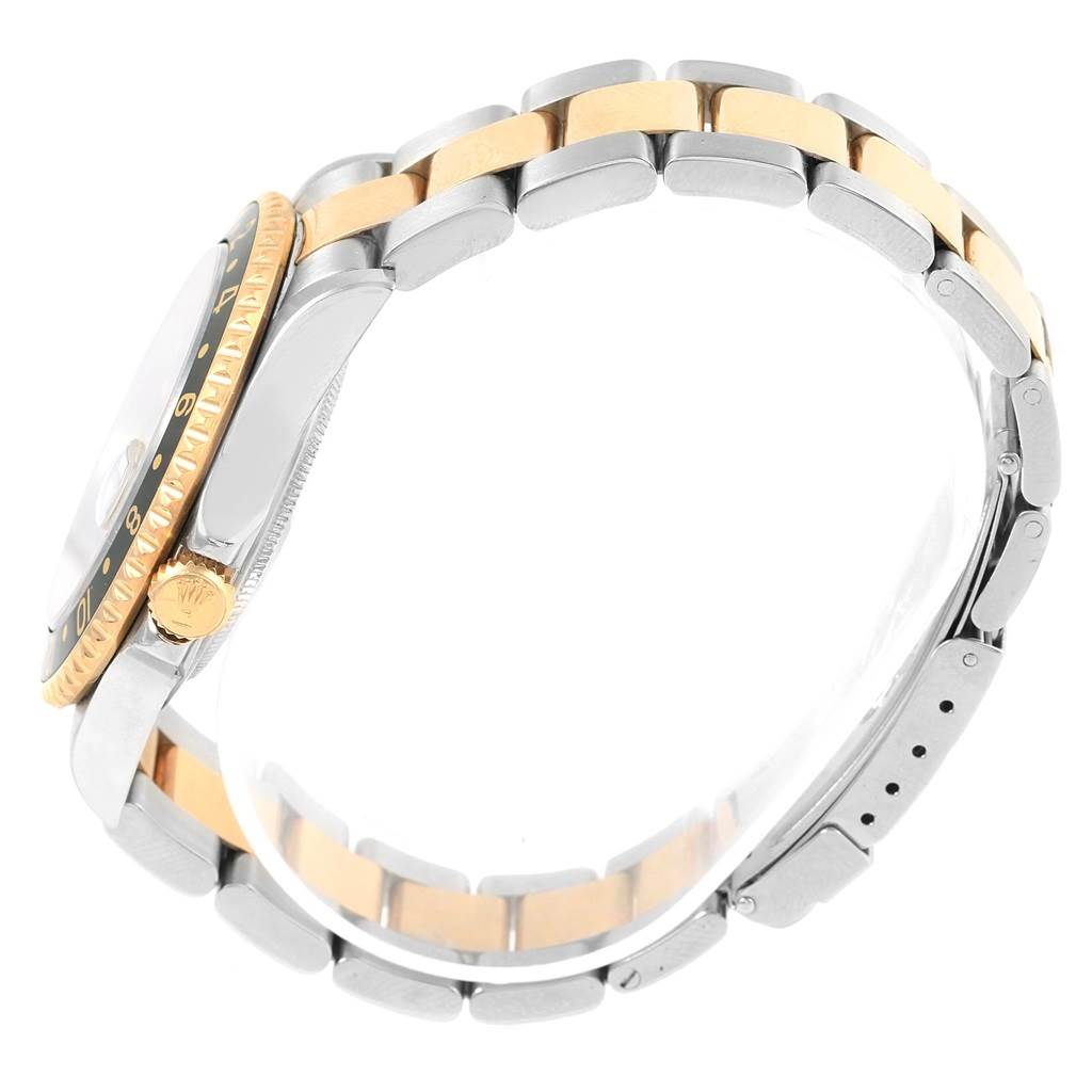 This side-angle view of the Rolex GMT-Master 16713 Men's Stainless Steel Black Dial 16713 Men's Stainless Steel Black Dial showcases the two-tone bracelet, bezel, and crown.