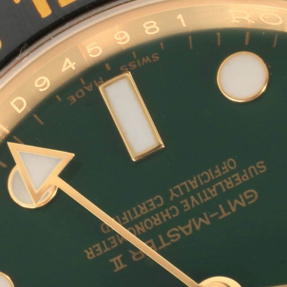 A close-up of the dial and GMT hand of a Rolex GMT-Master 116718 Men's Yellow Gold Green Dial 116718 Men's Yellow Gold Green Dial II, showing partial indices and text details.
