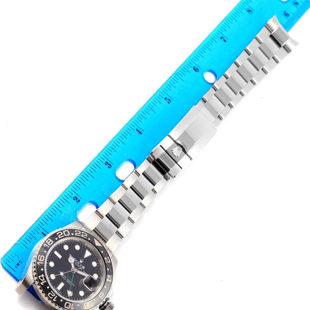 The image shows a top-down view of a Rolex GMT-Master 116710 Men's Stainless Steel Black Dial 116710 Men's Stainless Steel Black Dial watch, featuring its face, bezel, and metal bracelet placed next to a ruler.