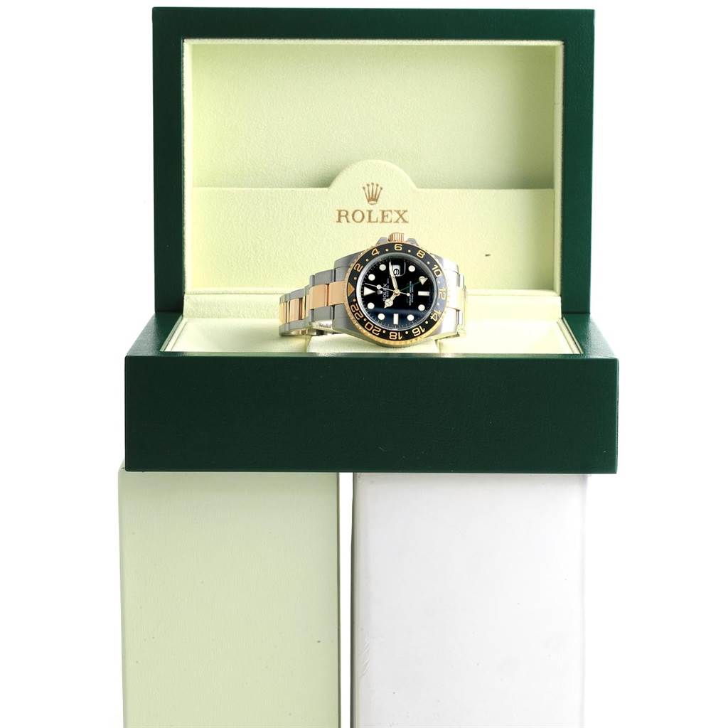 The Rolex GMT-Master 116713 Men
s Stainless Steel Black Dial 116713 Men
s Stainless Steel Black Dial watch is displayed front-facing inside an open green and cream Rolex box.