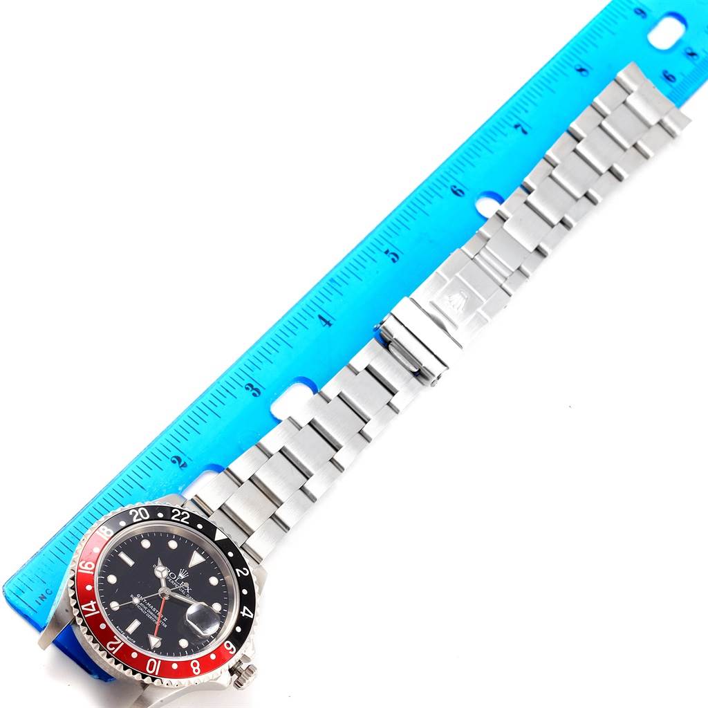 This image shows a top-down angle of a Rolex GMT-Master 16710 Men's Stainless Steel Black Dial 16710 Men's Stainless Steel Black Dial watch alongside a blue ruler.