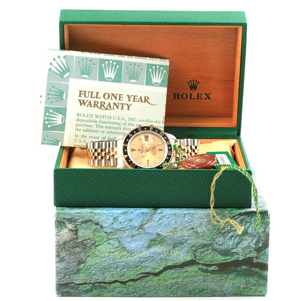 The image shows a Rolex GMT-Master 16713 Men's Steel and Gold (two tone) Champagne Dial 16713 Men's Steel and Gold (two tone) Champagne Dial watch and accessories placed inside an open box, displaying the warranty card and various tags.