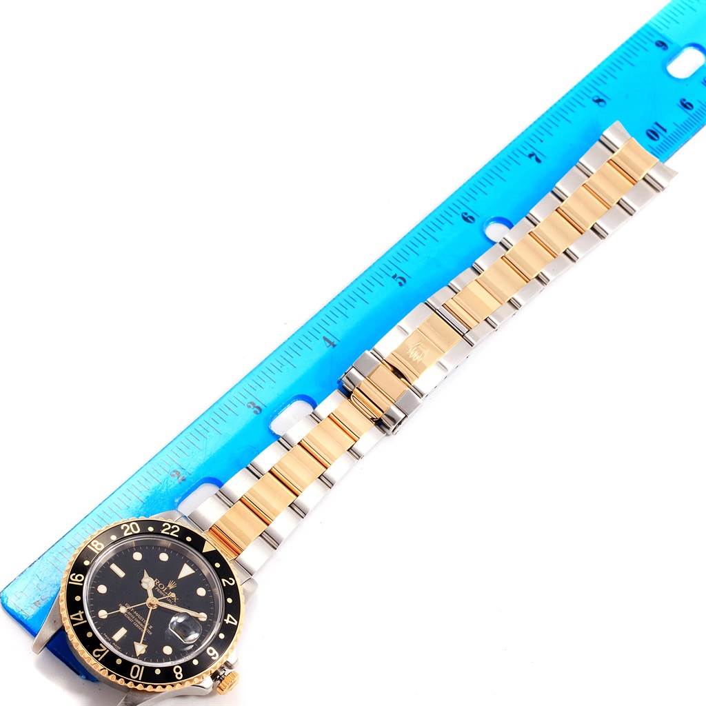 The image shows a Rolex GMT-Master 16713 Men's Stainless Steel Black Dial 16713 Men's Stainless Steel Black Dial watch laid flat next to a ruler, displaying the dial, bezel, and bracelet.