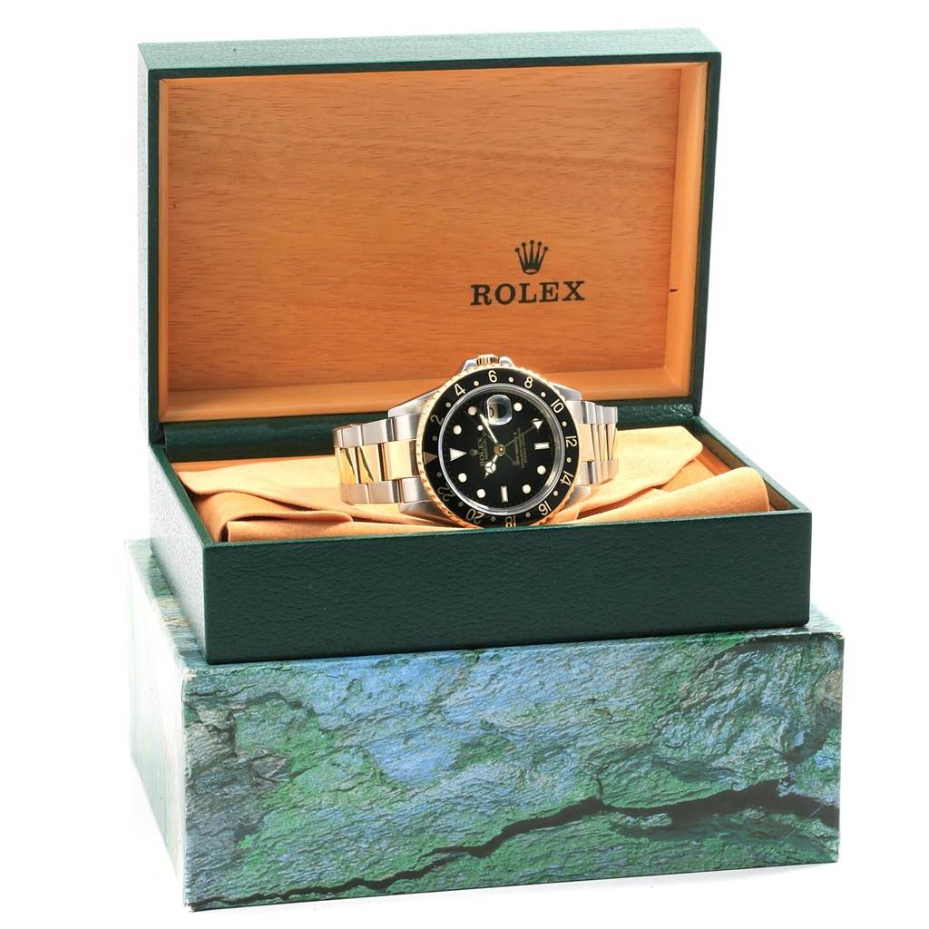 The Rolex GMT-Master 16713 Men's Stainless Steel Black Dial 16713 Men's Stainless Steel Black Dial watch is shown front-facing inside its open green and wood-colored box.