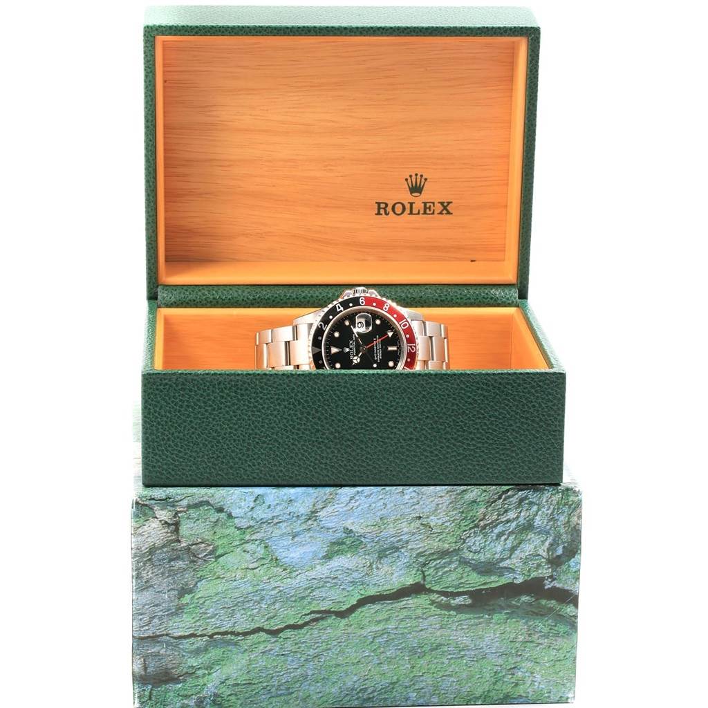 The Rolex GMT-Master 16710 Men's Stainless Steel Black Dial 16710 Men's Stainless Steel Black Dial watch is shown face up in its green and wooden display box, revealing the bezel and part of the bracelet.
