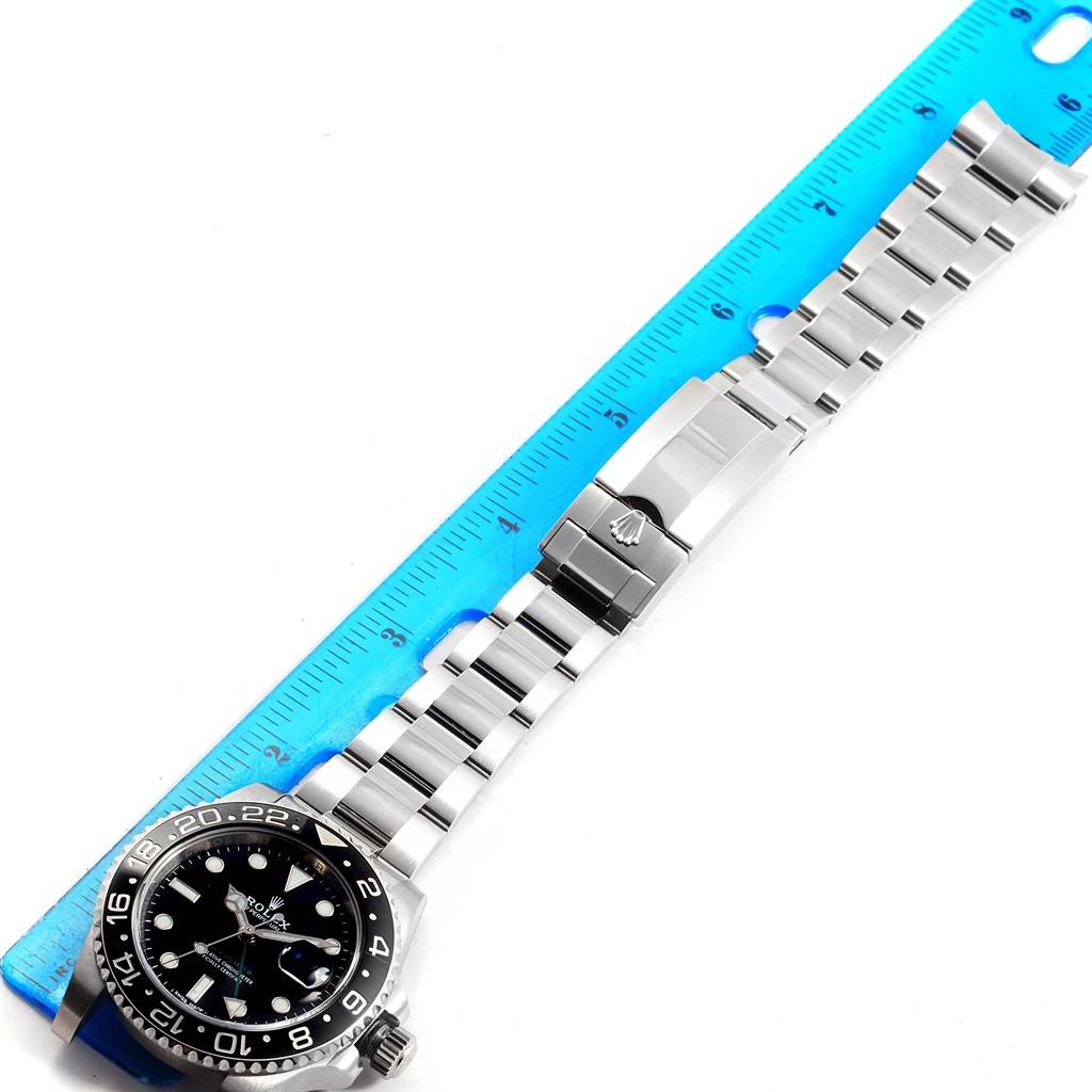 The image shows a Rolex GMT-Master 116710 Men
s Stainless Steel Black Dial 116710 Men
s Stainless Steel Black Dial watch laid flat with a blue ruler parallel to its stainless steel bracelet.