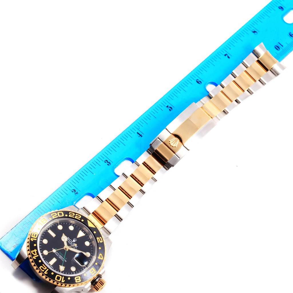 The image shows a Rolex GMT-Master 116713 Men's Stainless Steel Black Dial 116713 Men's Stainless Steel Black Dial watch at a top-down angle next to a blue ruler, with its face and bracelet visible.