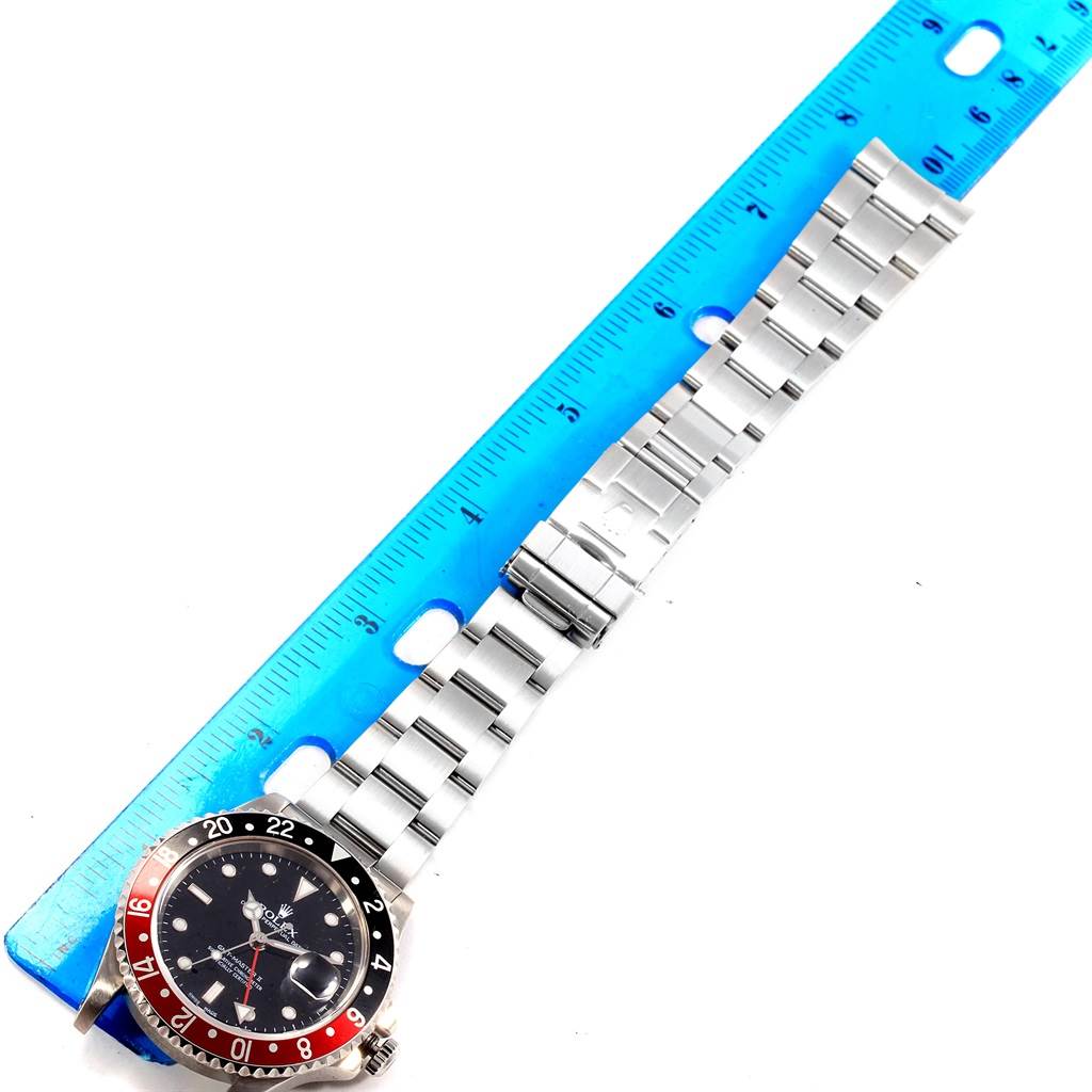The image shows a Rolex GMT-Master 16710 Men's Stainless Steel Black Dial 16710 Men's Stainless Steel Black Dial watch lying flat with its stainless steel bracelet extended alongside a blue ruler.
