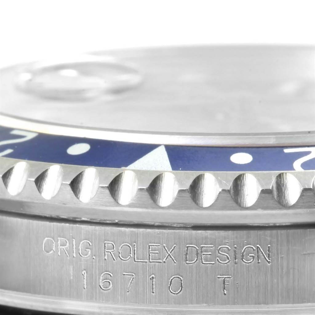 This close-up image of a Rolex GMT-Master 16710 Men's Stainless Steel Black Dial 16710 Men's Stainless Steel Black Dial shows the edge of the bezel and part of the watch case with "ORIG. ROLEX DESIGN."