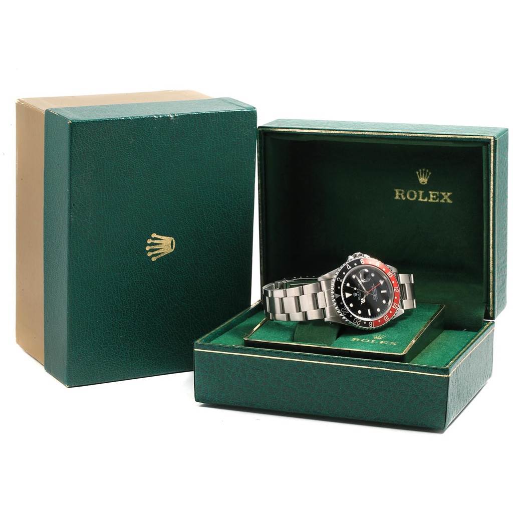 The Rolex GMT-Master 16700 Men's Stainless Steel Black Dial 16700 Men's Stainless Steel Black Dial watch is shown at an angle inside an open green Rolex box, with its bracelet and black and red bezel visible.