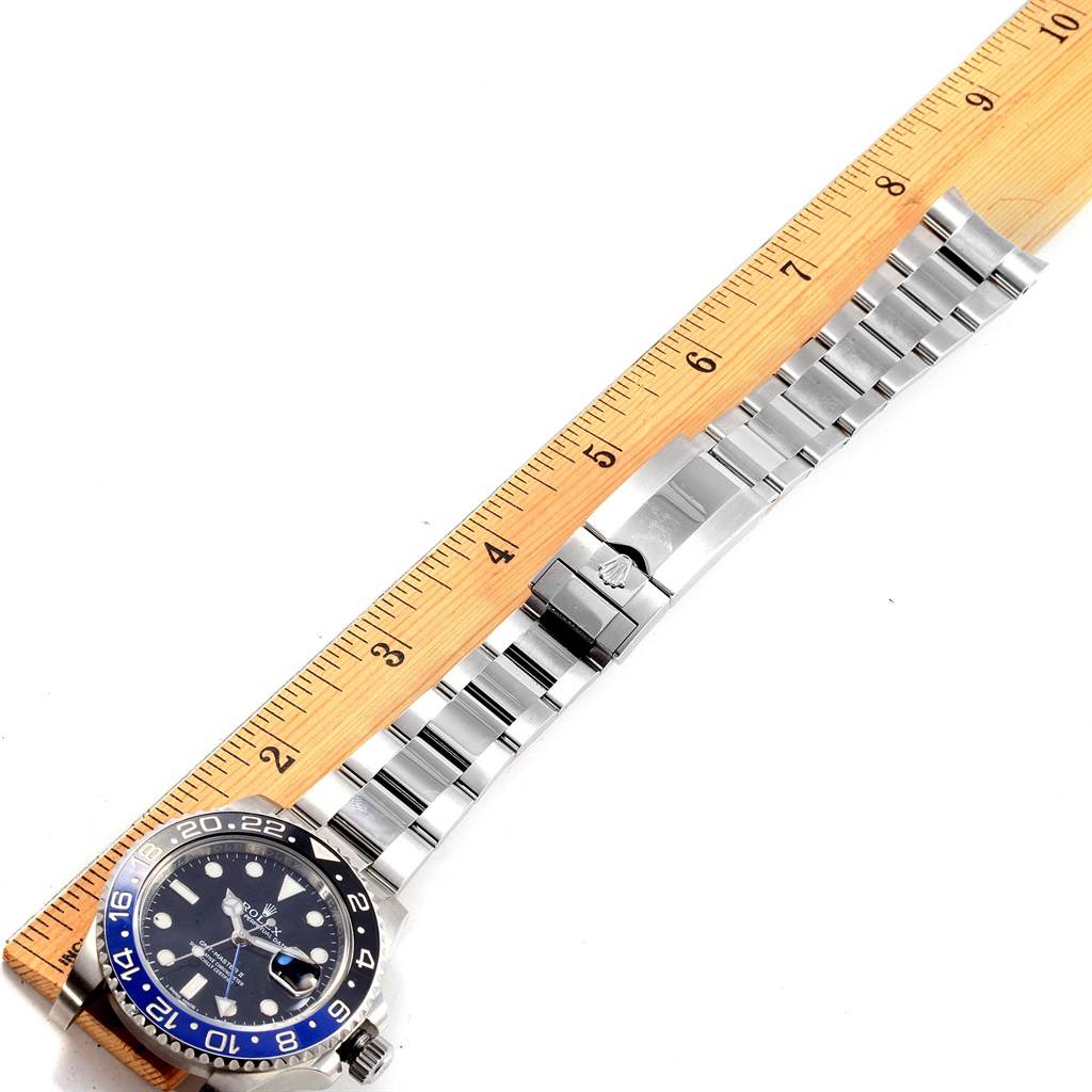 The Rolex GMT-Master 116710 Men's Stainless Steel Black Dial 116710 Men's Stainless Steel Black Dial watch is shown at a diagonal angle, with the face, bezel, and part of the bracelet visible next to a wooden ruler.