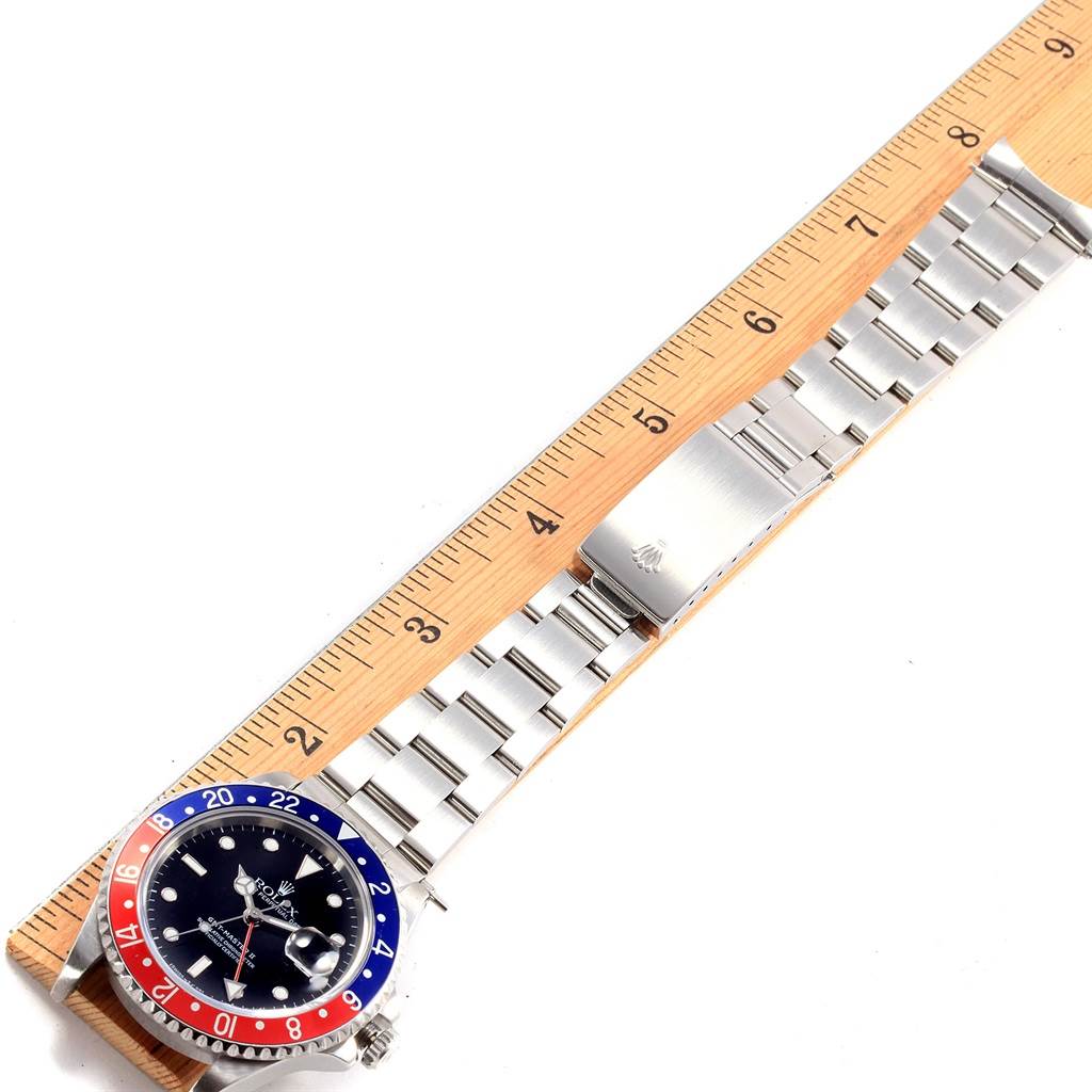 The Rolex GMT-Master 16710 Men
s Stainless Steel Black Dial 16710 Men
s Stainless Steel Black Dial watch is shown from the top angle, displaying the face, bezel, and metal bracelet alongside a ruler.