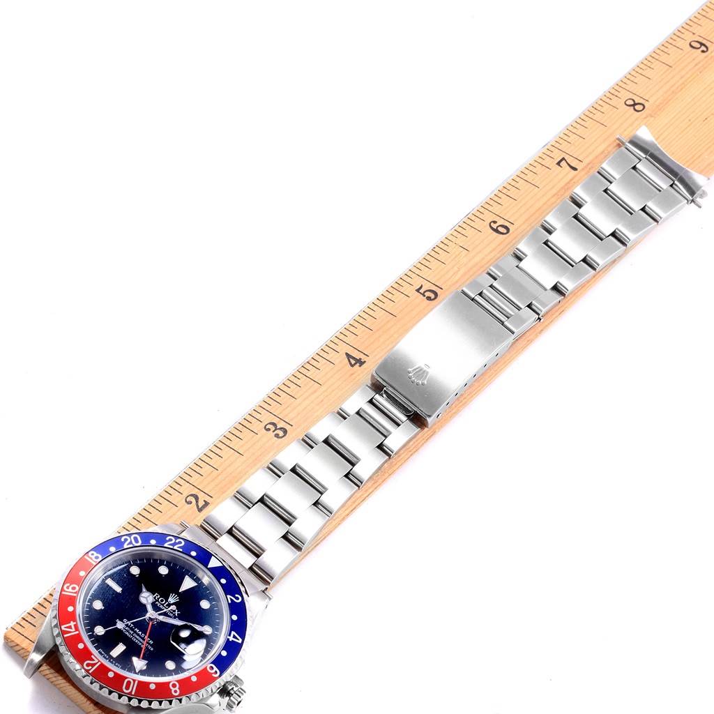 This image shows a top view of a Rolex GMT-Master 16700 Men's Stainless Steel Black Dial 16700 Men's Stainless Steel Black Dial watch, highlighting the dial, bezel, and bracelet next to a ruler for scale.