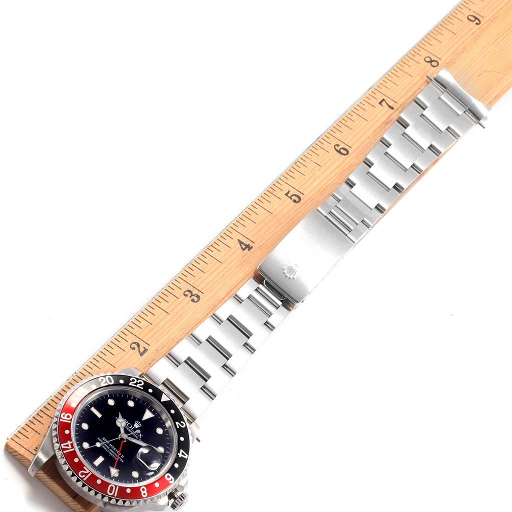 This image shows a Rolex GMT-Master 16710 Men's Stainless Steel Black Dial 16710 Men's Stainless Steel Black Dial watch laid flat, showcasing its bezel, dial, and stainless-steel bracelet with a ruler for scale.