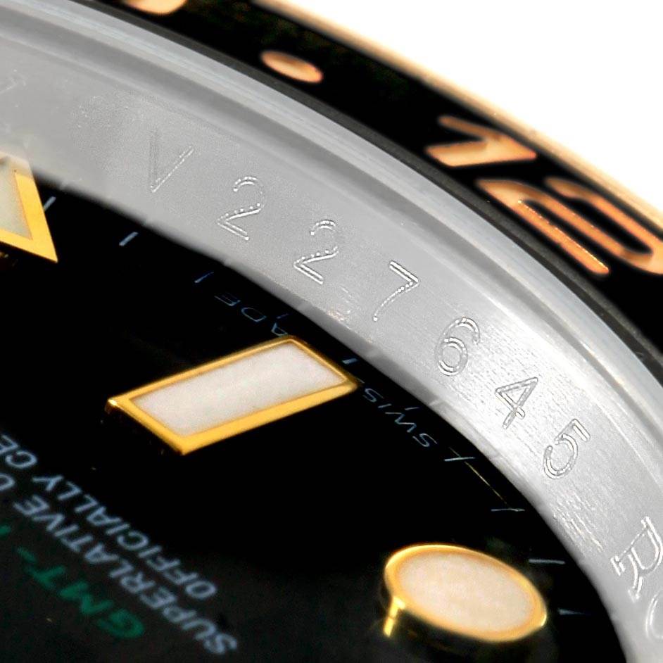 This close-up image of a Rolex GMT-Master 116713 Men's Stainless Steel Black Dial 116713 Men's Stainless Steel Black Dial watch shows the bezel, part of the dial, and the serial number engraving.