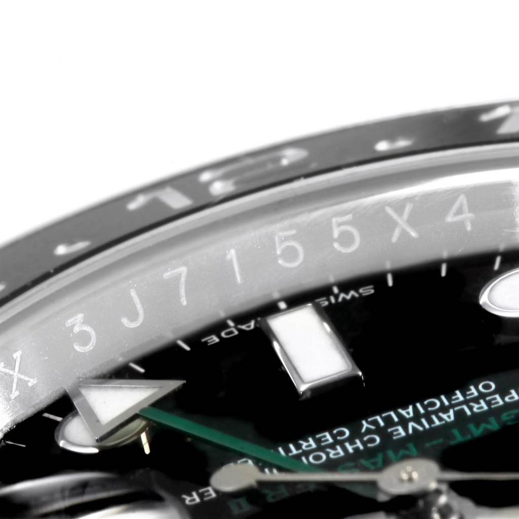 The image shows a close-up of the Rolex GMT-Master 116710 Men's Stainless Steel Black Dial 116710 Men's Stainless Steel Black Dial watch’s bezel and part of its dial, including indices and the GMT hand.