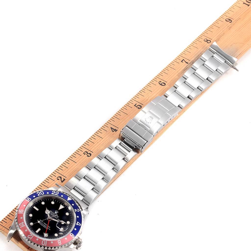 The image shows a Rolex GMT-Master 16700 Men's Stainless Steel Black Dial 16700 Men's Stainless Steel Black Dial watch laid flat next to a ruler, displaying the face, bezel, and bracelet.