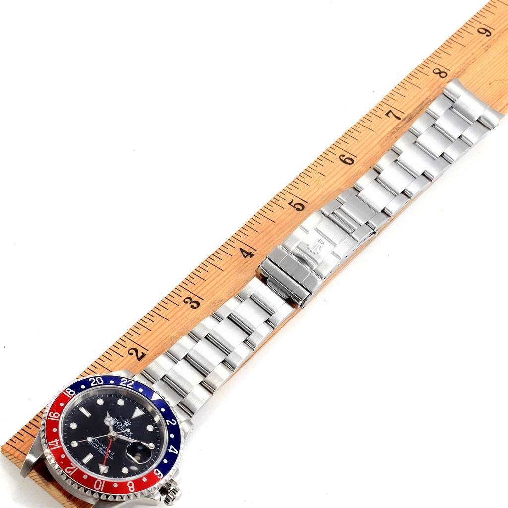 The image shows a top-down view of a Rolex GMT-Master 16710 Men's Stainless Steel Black Dial 16710 Men's Stainless Steel Black Dial watch with a "Pepsi" bezel, alongside a wooden ruler.