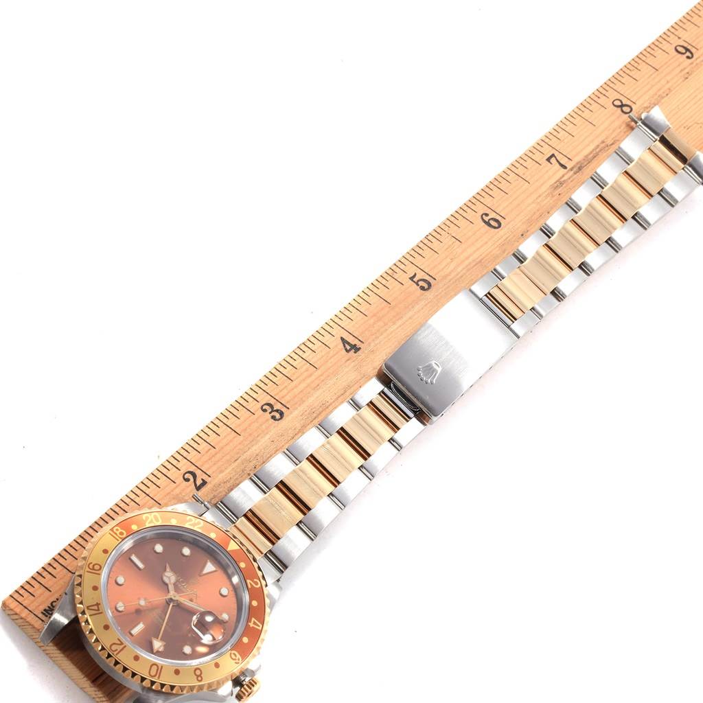 The image shows a Rolex GMT-Master 16713 Men's Stainless Steel Brown Dial 16713 Men's Stainless Steel Brown Dial watch laid flat, highlighting the face, bezel, and two-tone bracelet, alongside a ruler for reference.