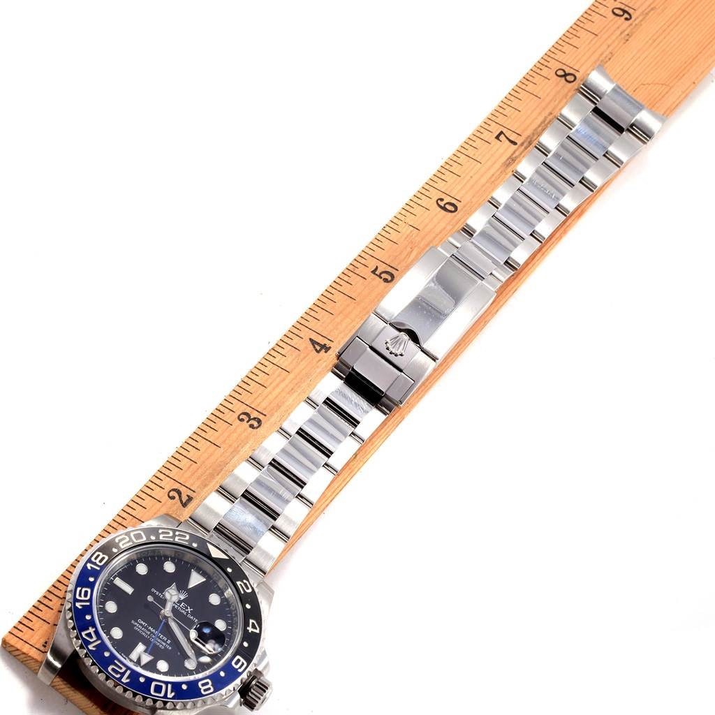 The image shows a top-down view of a Rolex GMT-Master 116710 Men's Stainless Steel Black Dial 116710 Men's Stainless Steel Black Dial watch with its stainless steel bracelet placed alongside a ruler.