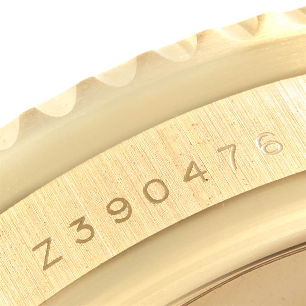 The image shows a close-up of the Rolex GMT-Master 116718 Men
s Yellow Gold Black Dial 116718 Men
s Yellow Gold Black Dial
s serial number and part of the bezel.