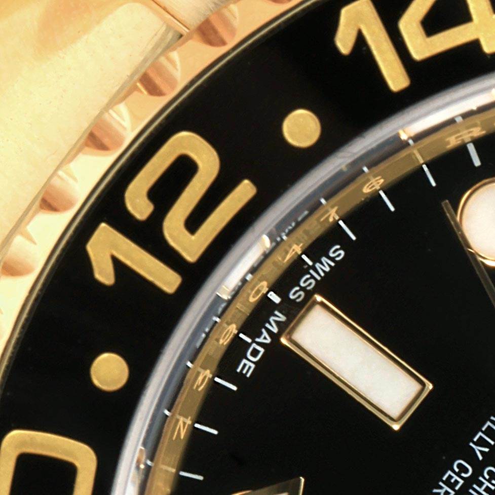 Close-up of the bezel and dial of a Rolex GMT-Master 116718 Men
s Yellow Gold Black Dial 116718 Men
s Yellow Gold Black Dial watch, showing the 12-hour marker and part of the date window.