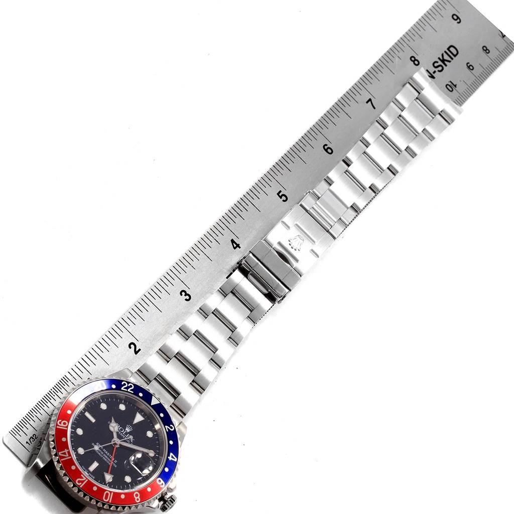 The image shows the Rolex GMT-Master 16710 Men's Stainless Steel Black Dial 16710 Men's Stainless Steel Black Dial watch from an overhead angle, displaying the face, bezel, and full metal bracelet alongside a ruler for scale.