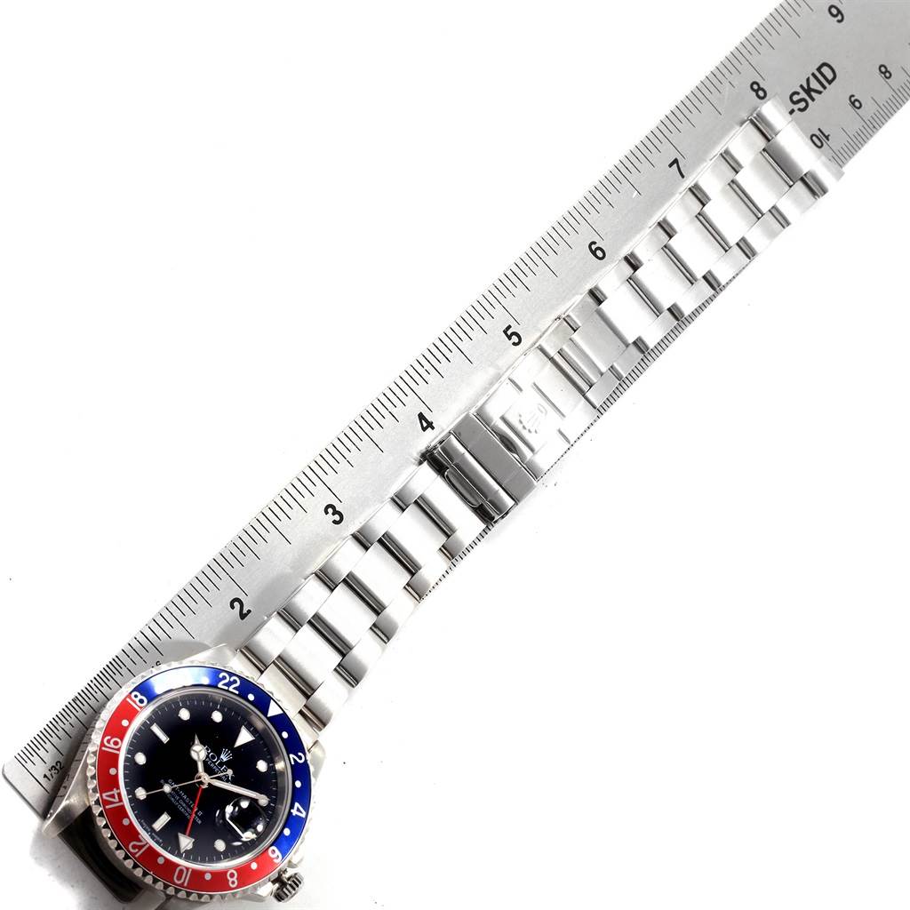 The image shows the face and entire bracelet of the Rolex GMT-Master 16710 Men's Stainless Steel Black Dial 16710 Men's Stainless Steel Black Dial watch laid next to a ruler for measurement.