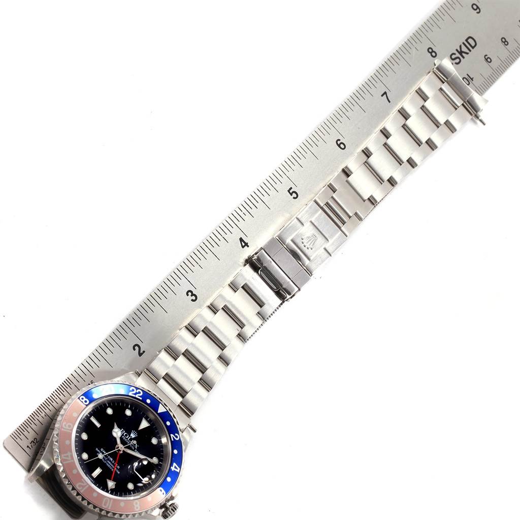 The image shows a Rolex GMT-Master 16700 Men's Stainless Steel Black Dial 16700 Men's Stainless Steel Black Dial watch laid flat next to a ruler, highlighting its bracelet and clasp.