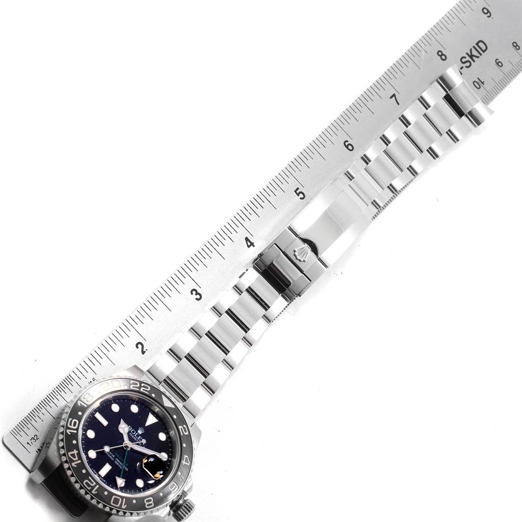 The image shows a Rolex GMT-Master 116710 Men
s Stainless Steel Black Dial 116710 Men
s Stainless Steel Black Dial watch face with its metal bracelet fully extended next to a ruler for measuring.