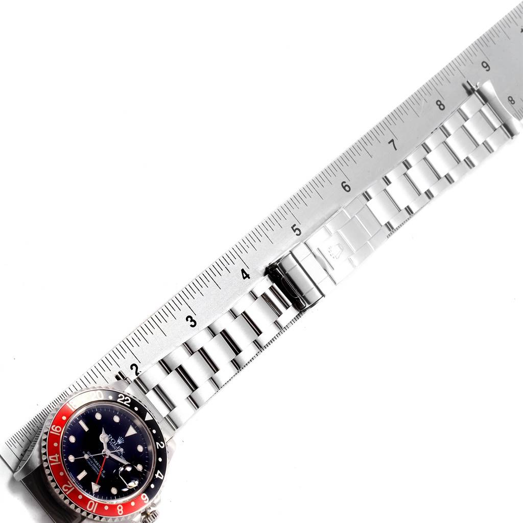 The image shows a side angle of a Rolex GMT-Master 16710 Men's Stainless Steel Black Dial 16710 Men's Stainless Steel Black Dial watch with its band laid against a ruler for measurement.