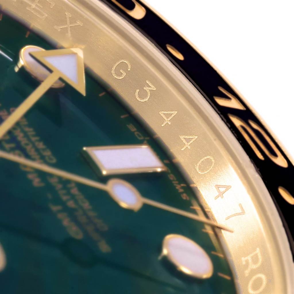 A close-up view of the Rolex GMT-Master 116718 Men's Yellow Gold Green Dial 116718 Men's Yellow Gold Green Dial watch shows the bezel, part of the dial, and the engraved serial number.
