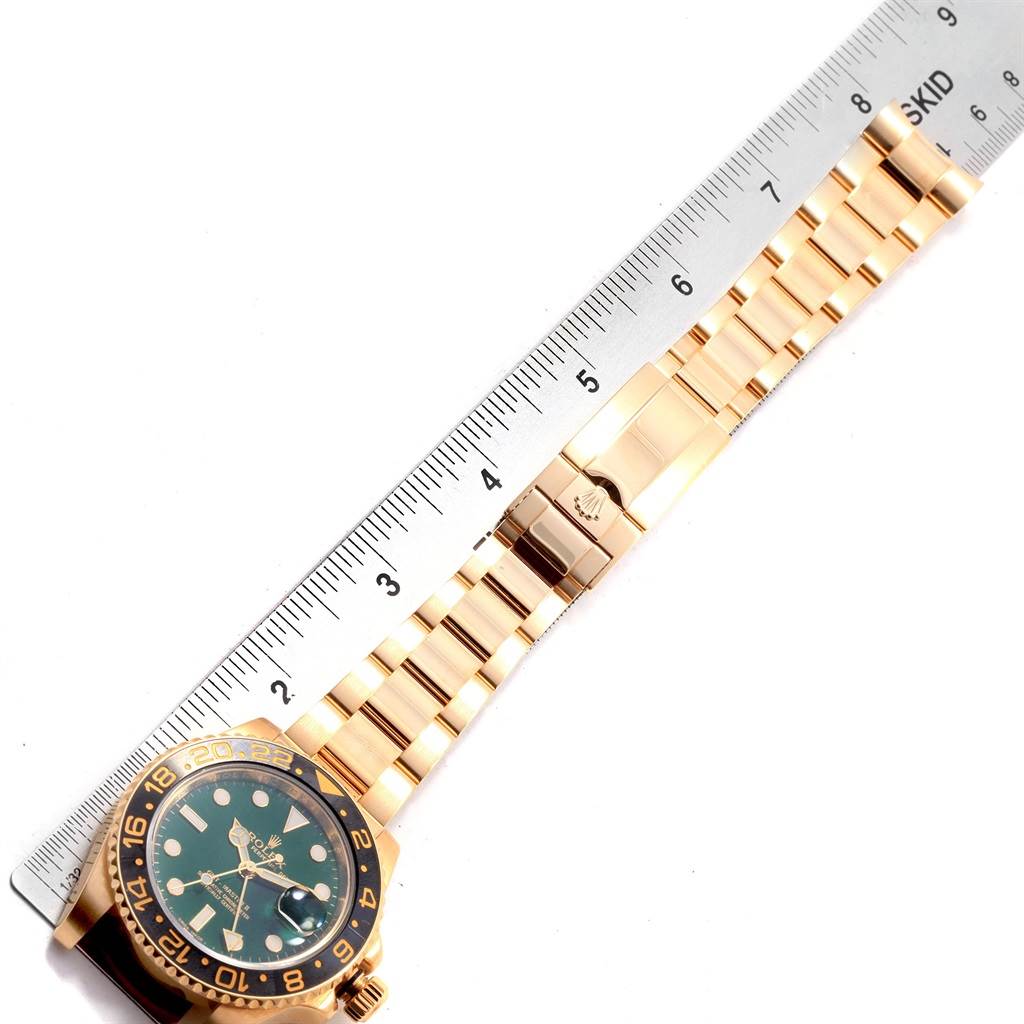 The image shows a Rolex GMT-Master 116718 Men's Yellow Gold Green Dial 116718 Men's Yellow Gold Green Dial watch laid flat next to a ruler, highlighting its bracelet and clasp.