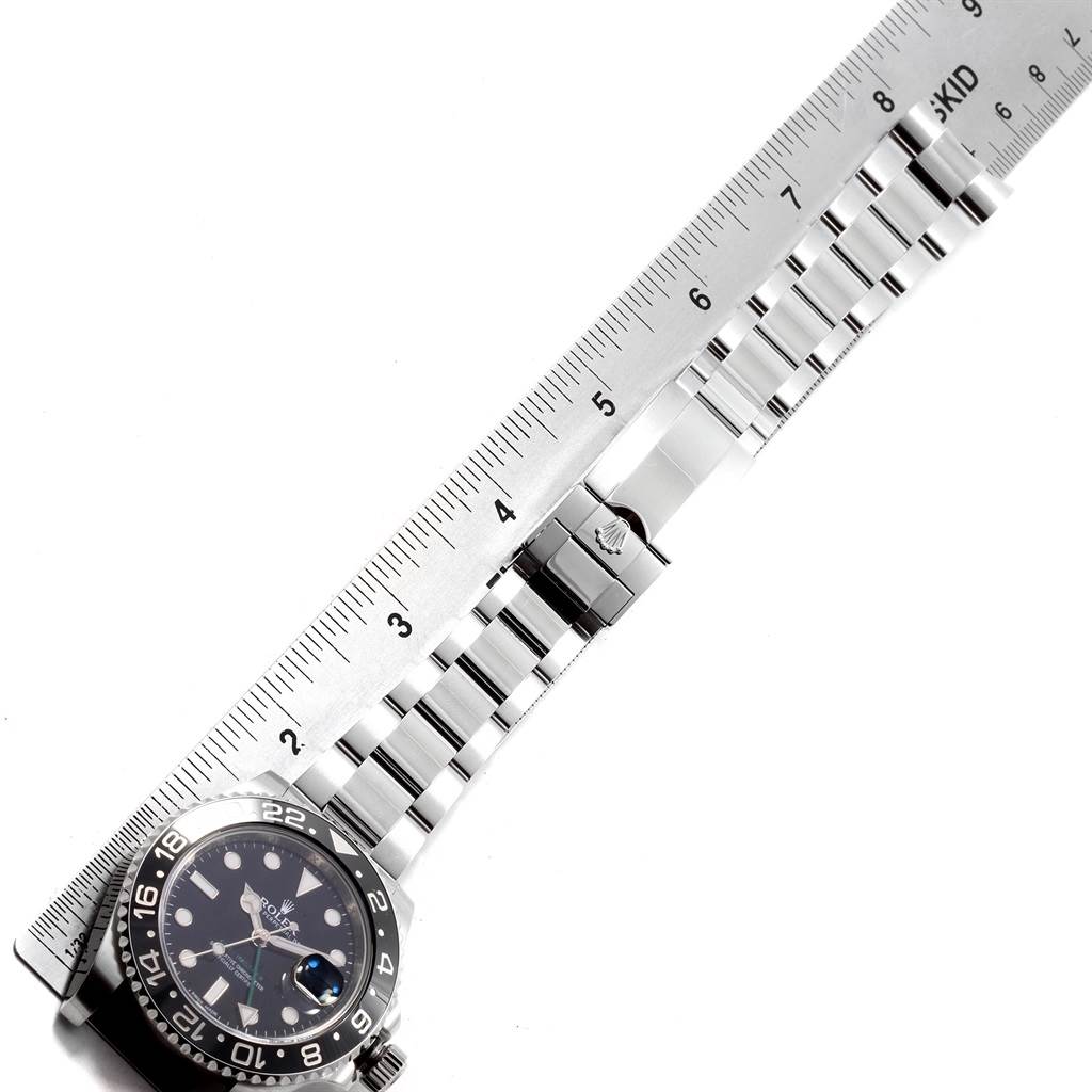 The image shows the face and bracelet of a Rolex GMT-Master 116710 Men's Stainless Steel Black Dial 116710 Men's Stainless Steel Black Dial watch next to a ruler, viewed from above.
