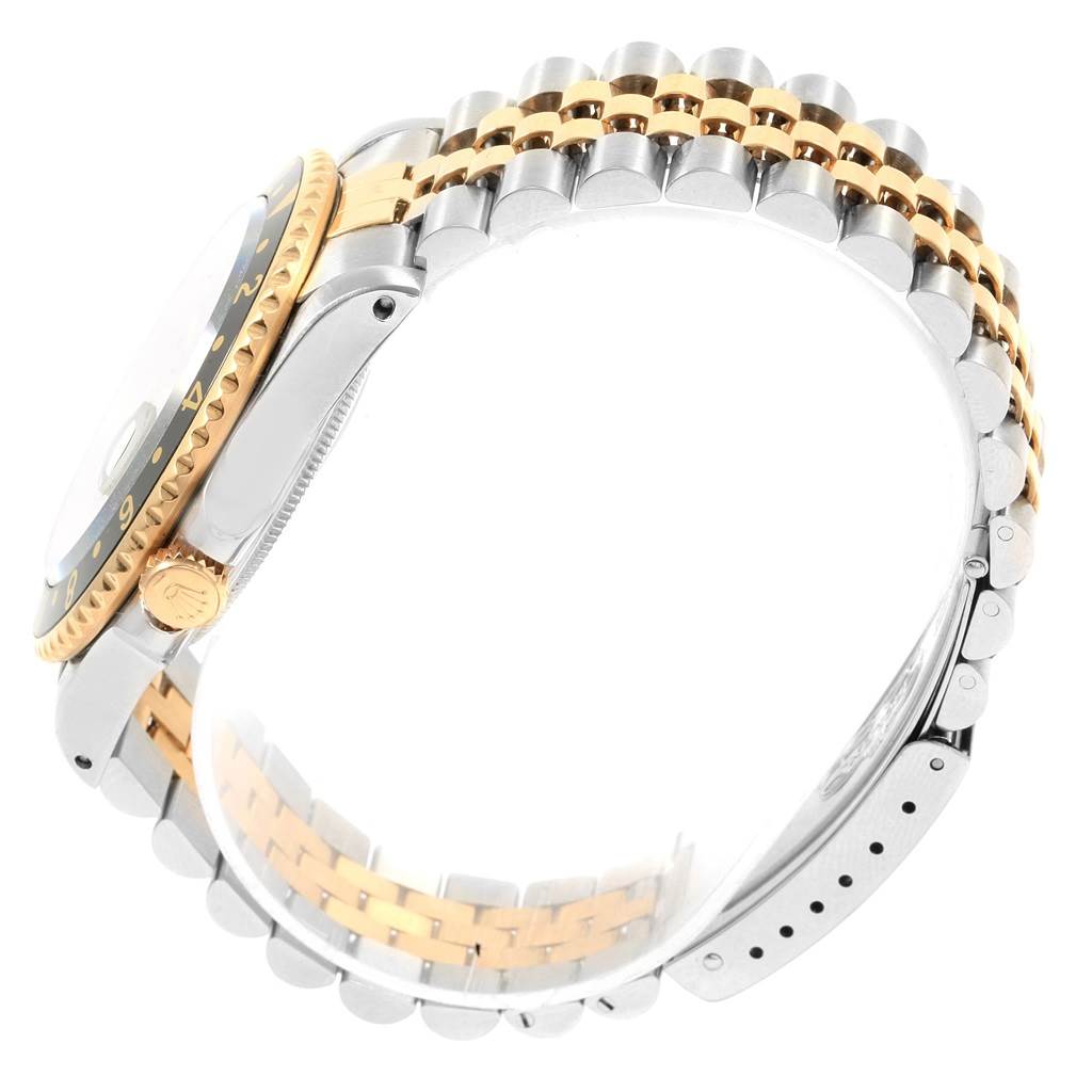 This side view of the Rolex GMT-Master 16713 Men's Stainless Steel Black Dial 16713 Men's Stainless Steel Black Dial watch shows the bezel, crown, and two-toned bracelet.