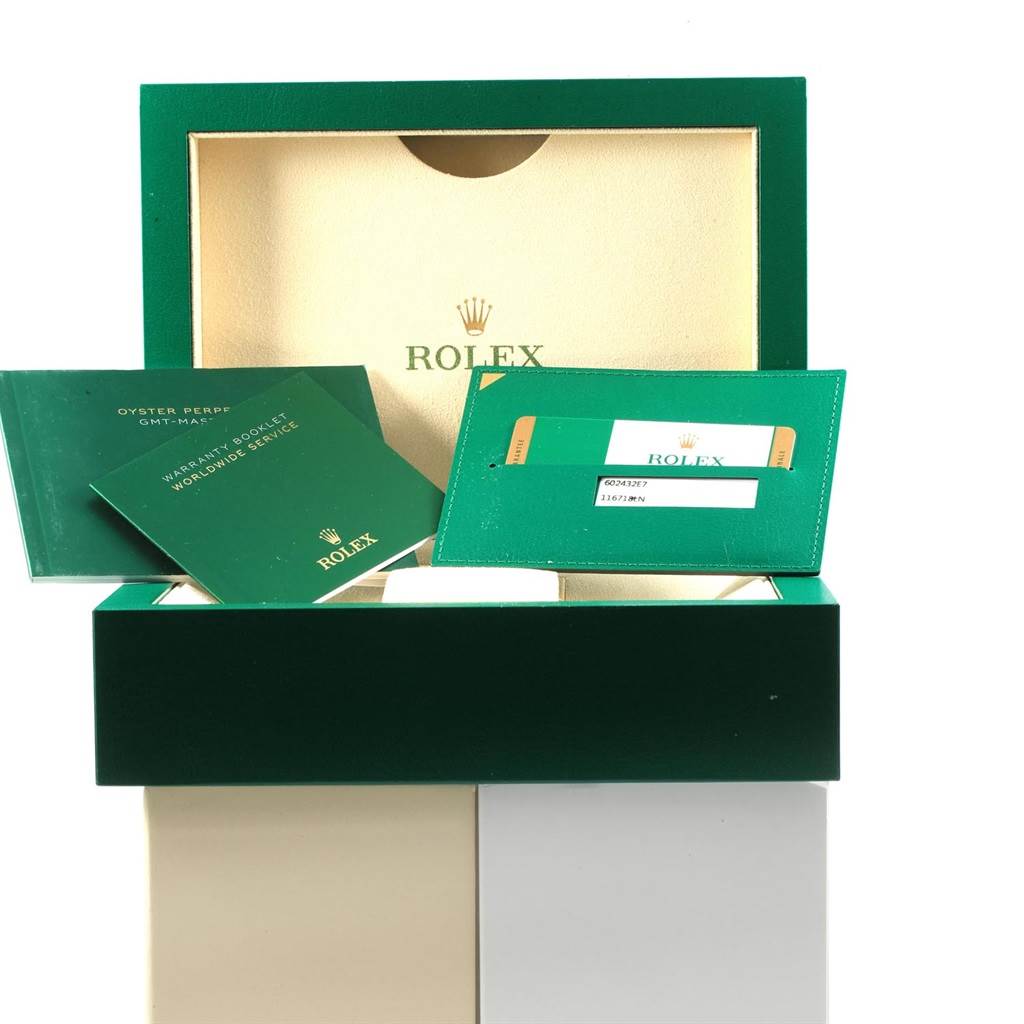 This image shows the open box, warranty booklet, and cardholder for the Rolex GMT-Master 116718LN Men's Yellow Gold Green Dial 116718LN Men's Yellow Gold Green Dial watch.