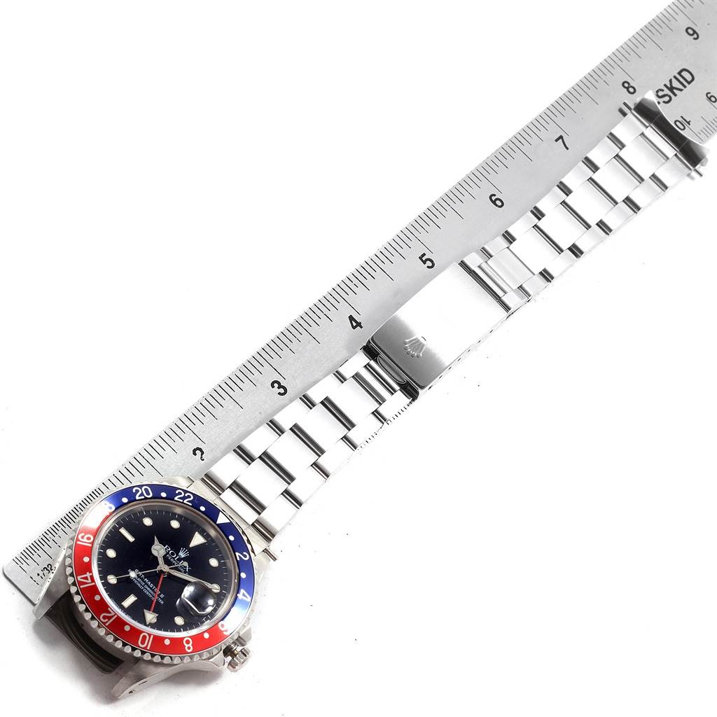 This image shows a top view of a Rolex GMT-Master 16710 Men's Stainless Steel Black Dial 16710 Men's Stainless Steel Black Dial watch laying flat, alongside a ruler for scale.
