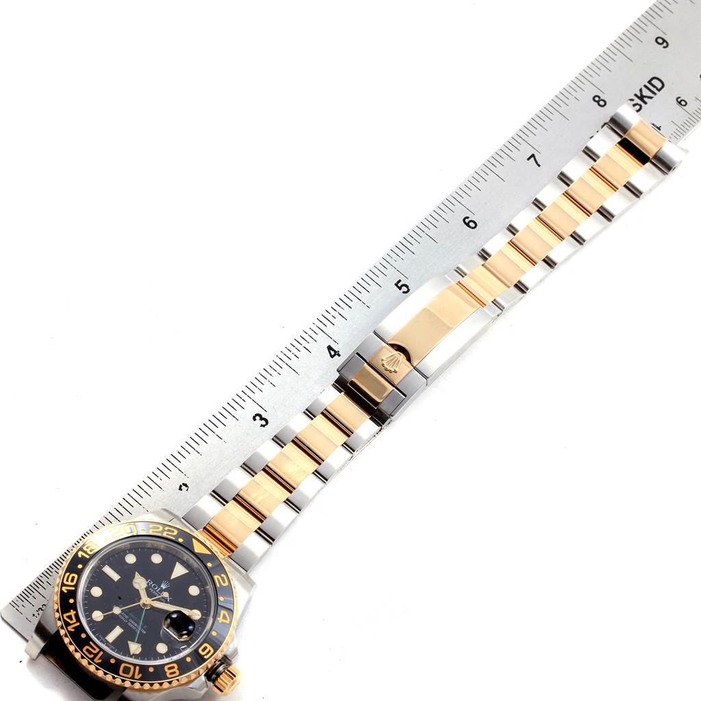 The image shows a Rolex GMT-Master 116713 Men
s Stainless Steel Black Dial 116713 Men
s Stainless Steel Black Dial watch laid flat with a ruler measuring its two-tone bracelet and clasp.