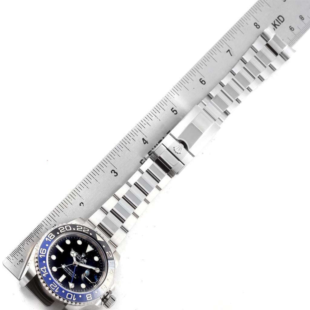 The image shows the Rolex GMT-Master 116710 Men's Stainless Steel Black Dial 116710 Men's Stainless Steel Black Dial watch face, bezel, and bracelet at an aerial angle next to a ruler for scale.