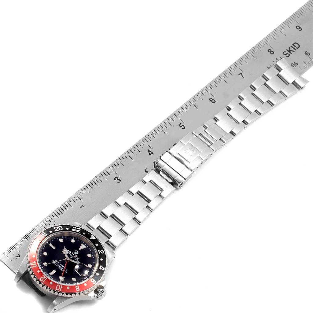 This image shows a top-down view of a Rolex GMT-Master 16710 Men's Stainless Steel Black Dial 16710 Men's Stainless Steel Black Dial watch with its bracelet laid next to a ruler.