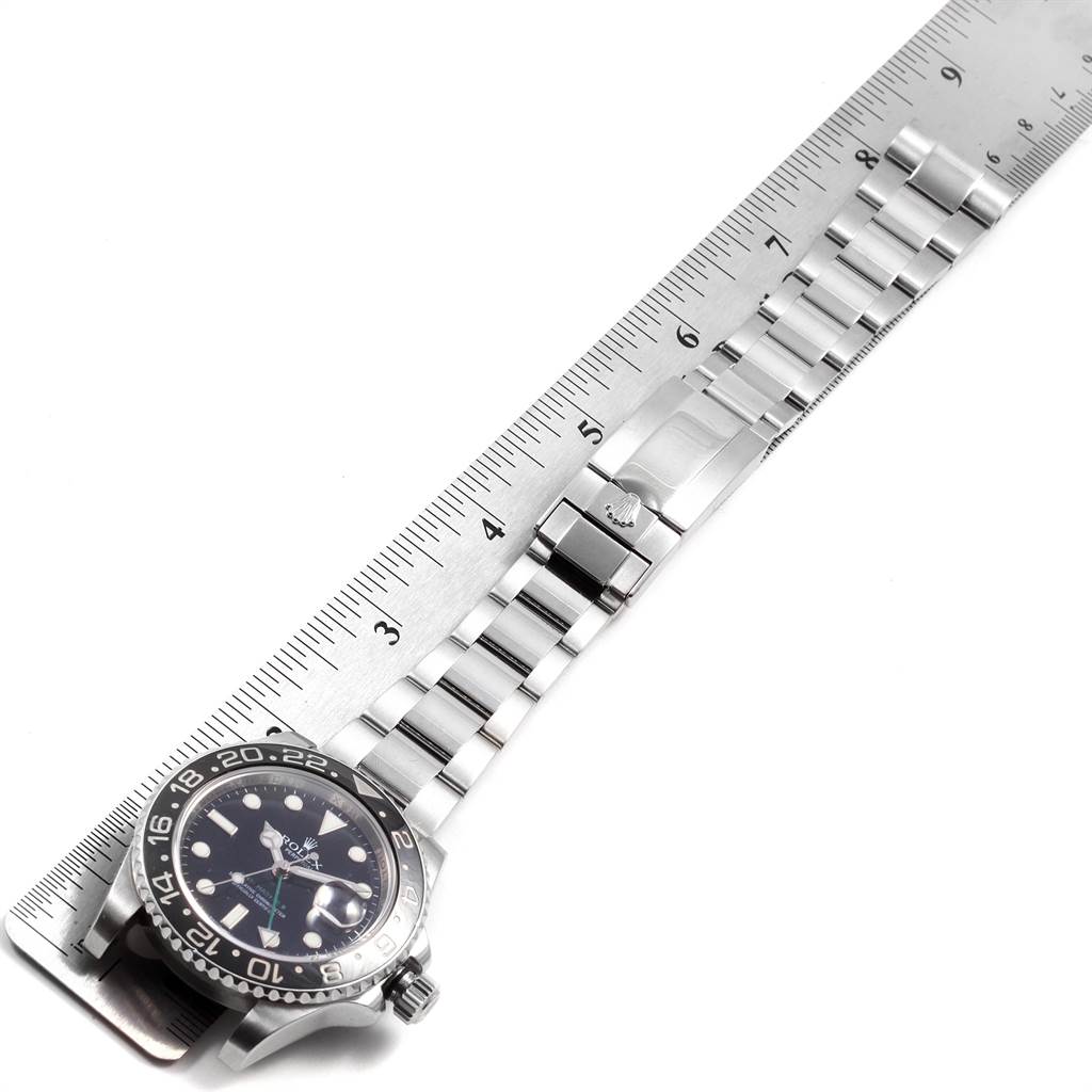 The image shows a top-down view of a Rolex GMT-Master 116710 Men's Stainless Steel Black Dial 116710 Men's Stainless Steel Black Dial watch, including its face, bezel, and metal bracelet alongside a ruler for scale.