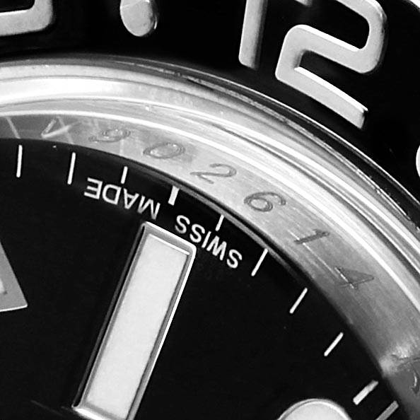 This close-up of the Rolex GMT-Master 116710 Men
s Stainless Steel Black Dial 116710 Men
s Stainless Steel Black Dial watch shows the top portion of the dial, including the "12" marker and "SWISS MADE" text.