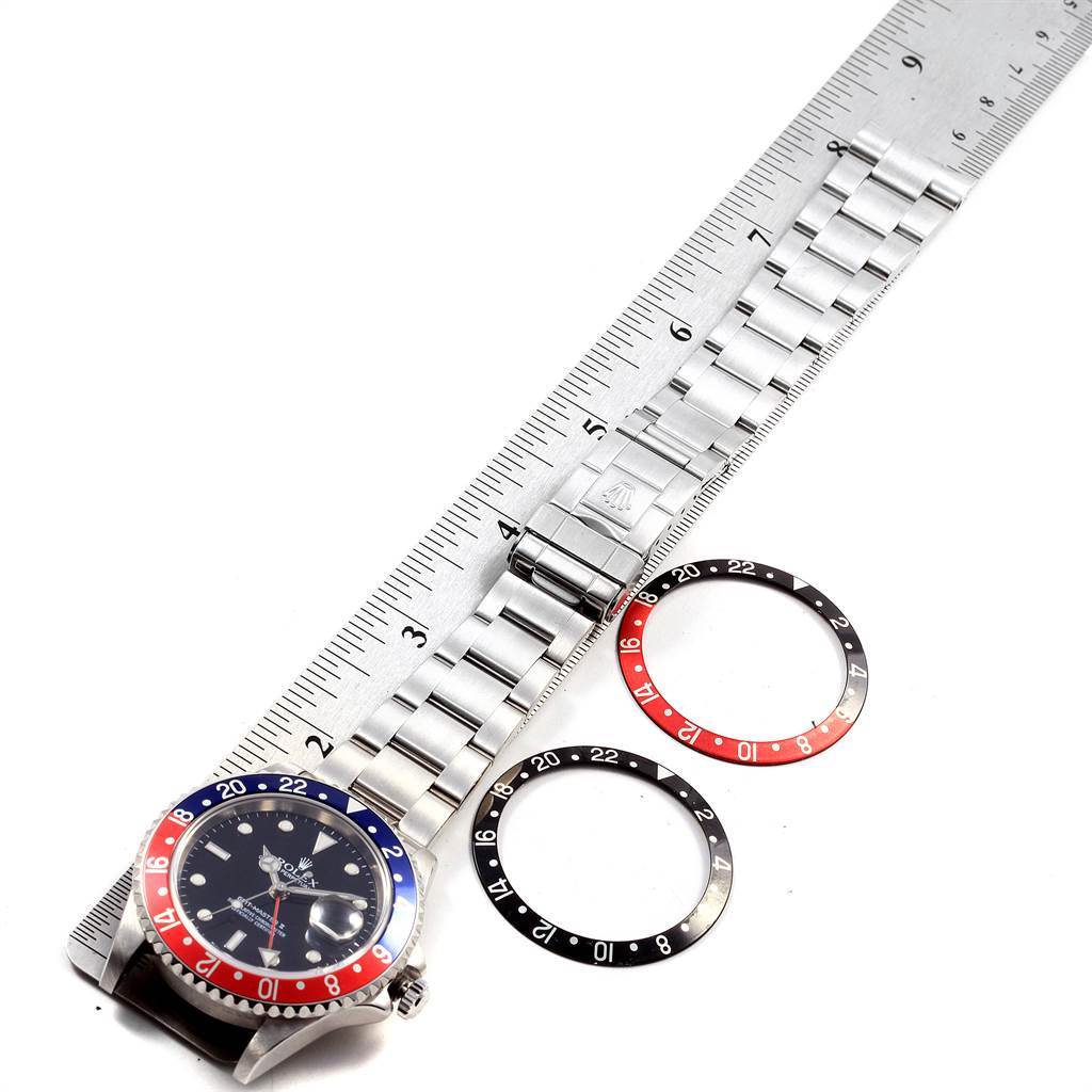 This image shows the Rolex GMT-Master 16710 Men's Stainless Steel Black Dial 16710 Men's Stainless Steel Black Dial watch placed next to a ruler, alongside two additional bezels.