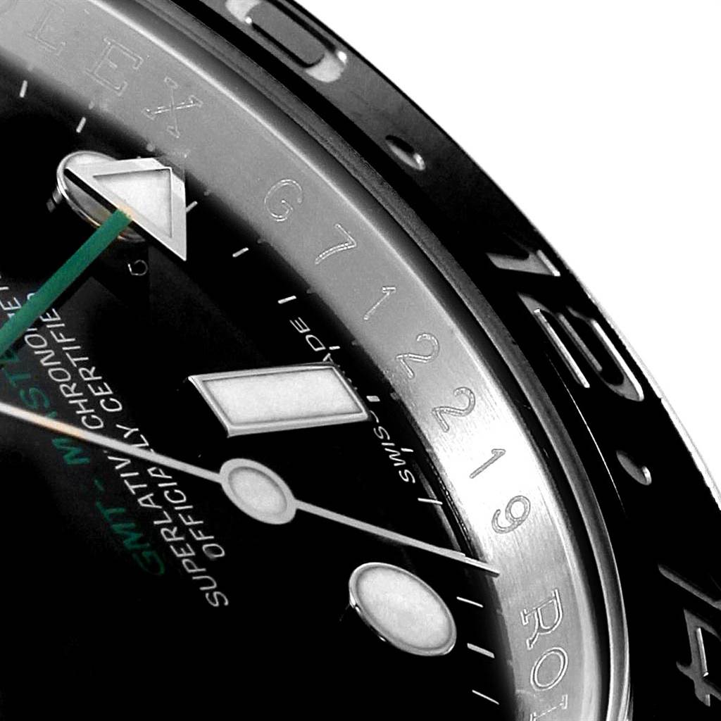This close-up image shows part of the dial, hands, and bezel of a Rolex GMT-Master 116710 Men's Stainless Steel Black Dial 116710 Men's Stainless Steel Black Dial watch at an angle highlighting the engravings.