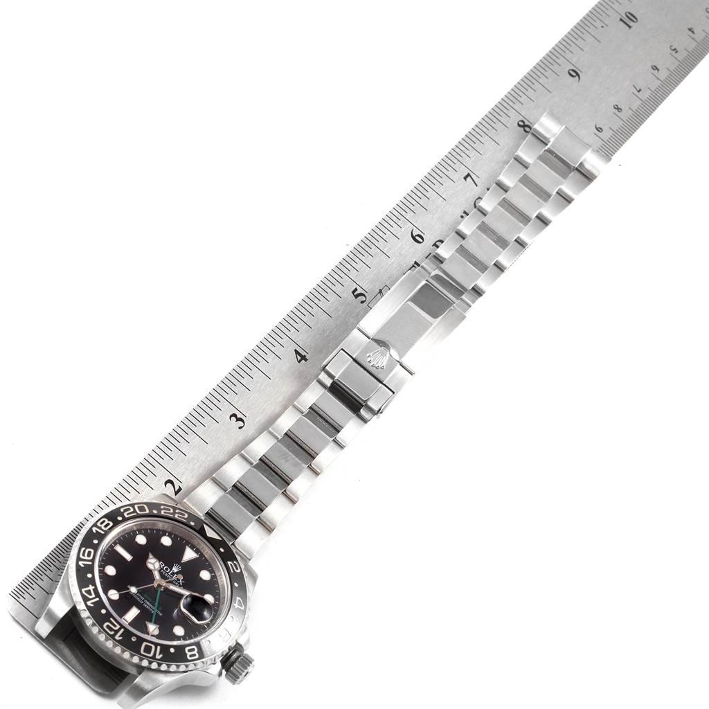 The image shows a Rolex GMT-Master 116710 Men's Stainless Steel Black Dial 116710 Men's Stainless Steel Black Dial watch laid next to a ruler, showcasing its face, bezel, and metal bracelet from a top-down angle.