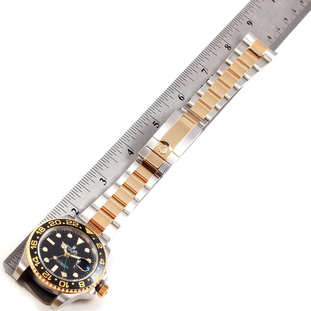 The Rolex GMT-Master 116713 Men's Stainless Steel Black Dial 116713 Men's Stainless Steel Black Dial watch is shown from above, displaying the face, bezel, and bracelet alongside a ruler for scale.