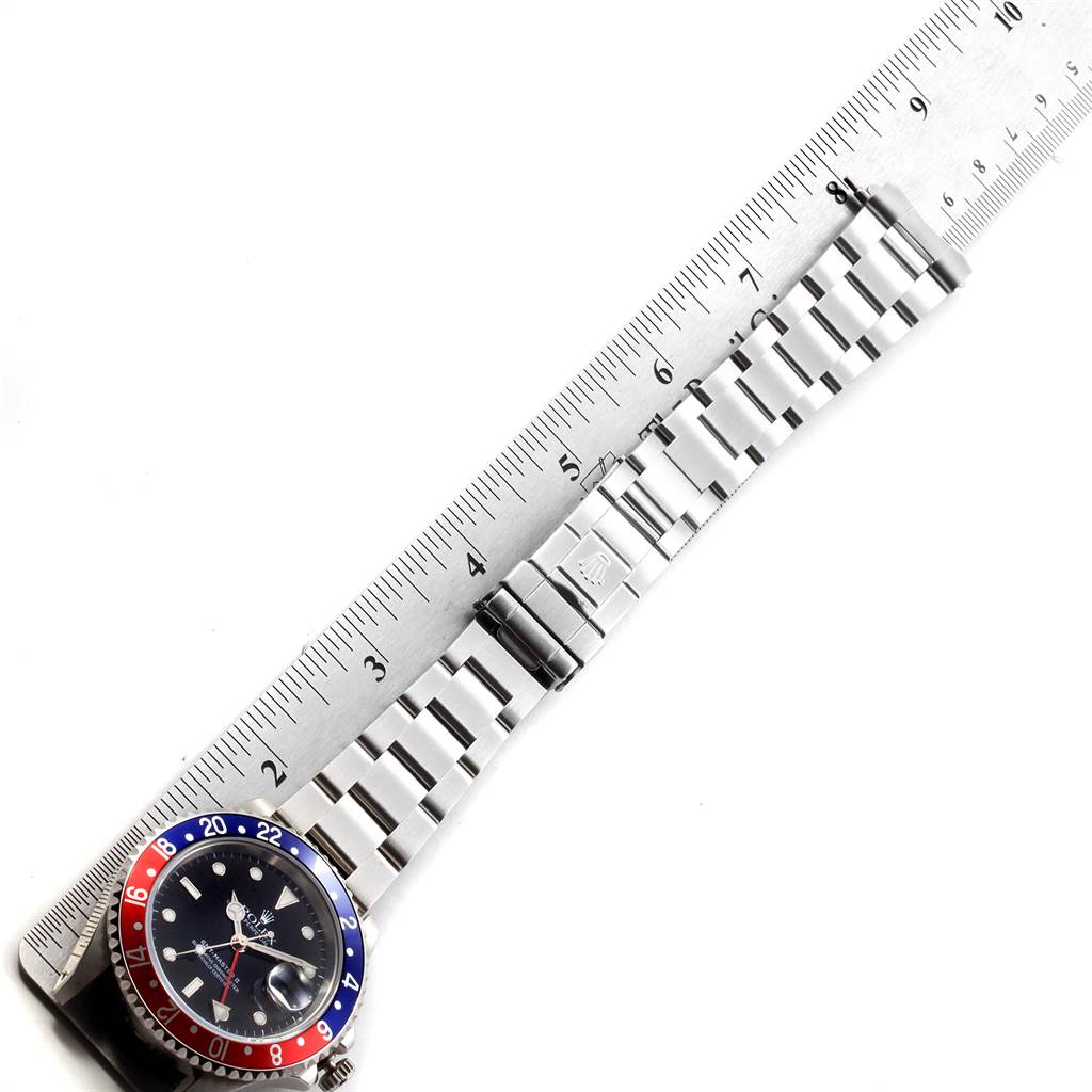 The image shows a Rolex GMT-Master 16710 Men's Stainless Steel Black Dial 16710 Men's Stainless Steel Black Dial watch placed alongside a ruler, highlighting its band and clasp.