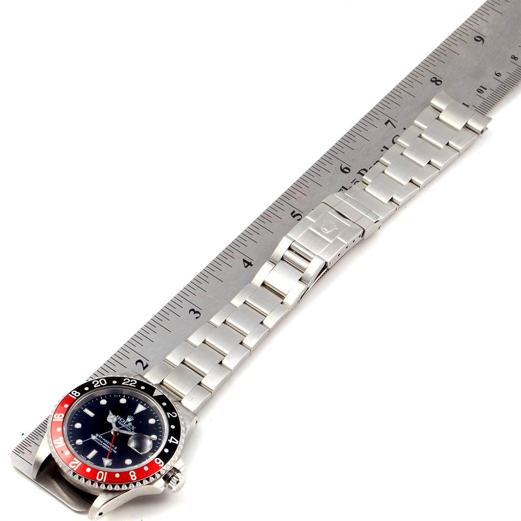 The image shows a top-down view of a Rolex GMT-Master 16710 Men's Stainless Steel Black Dial 16710 Men's Stainless Steel Black Dial watch with its stainless steel bracelet extended next to a ruler for scale.