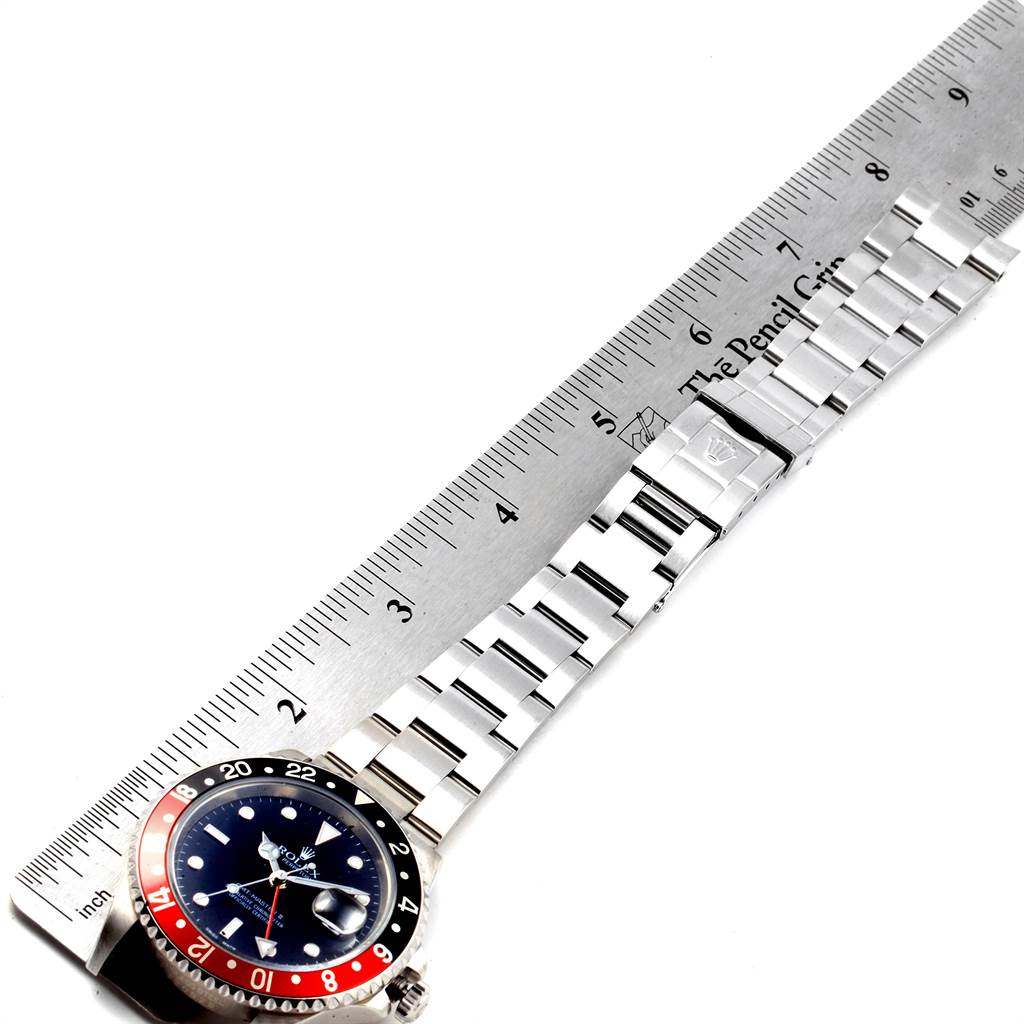 The image shows a Rolex GMT-Master 16710 Men
s Stainless Steel Black Dial 16710 Men
s Stainless Steel Black Dial watch laid flat next to a ruler, highlighting the face, bezel, and bracelet.