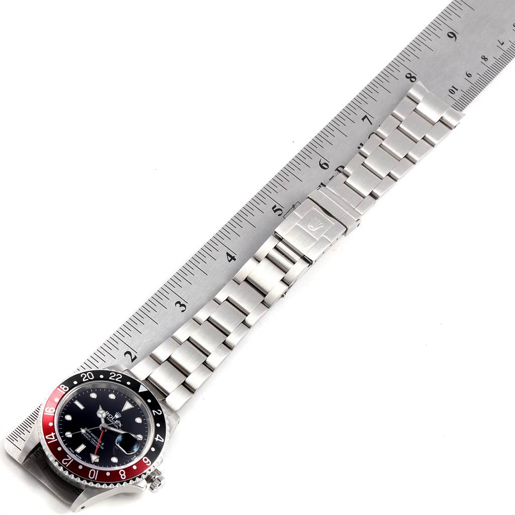 The image shows a top view of a Rolex GMT-Master 16710 Men's Stainless Steel Black Dial 16710 Men's Stainless Steel Black Dial watch, highlighting the face, bezel, and metal bracelet against a ruler.